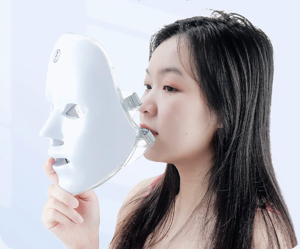 Person holding a white mask against a light gray background